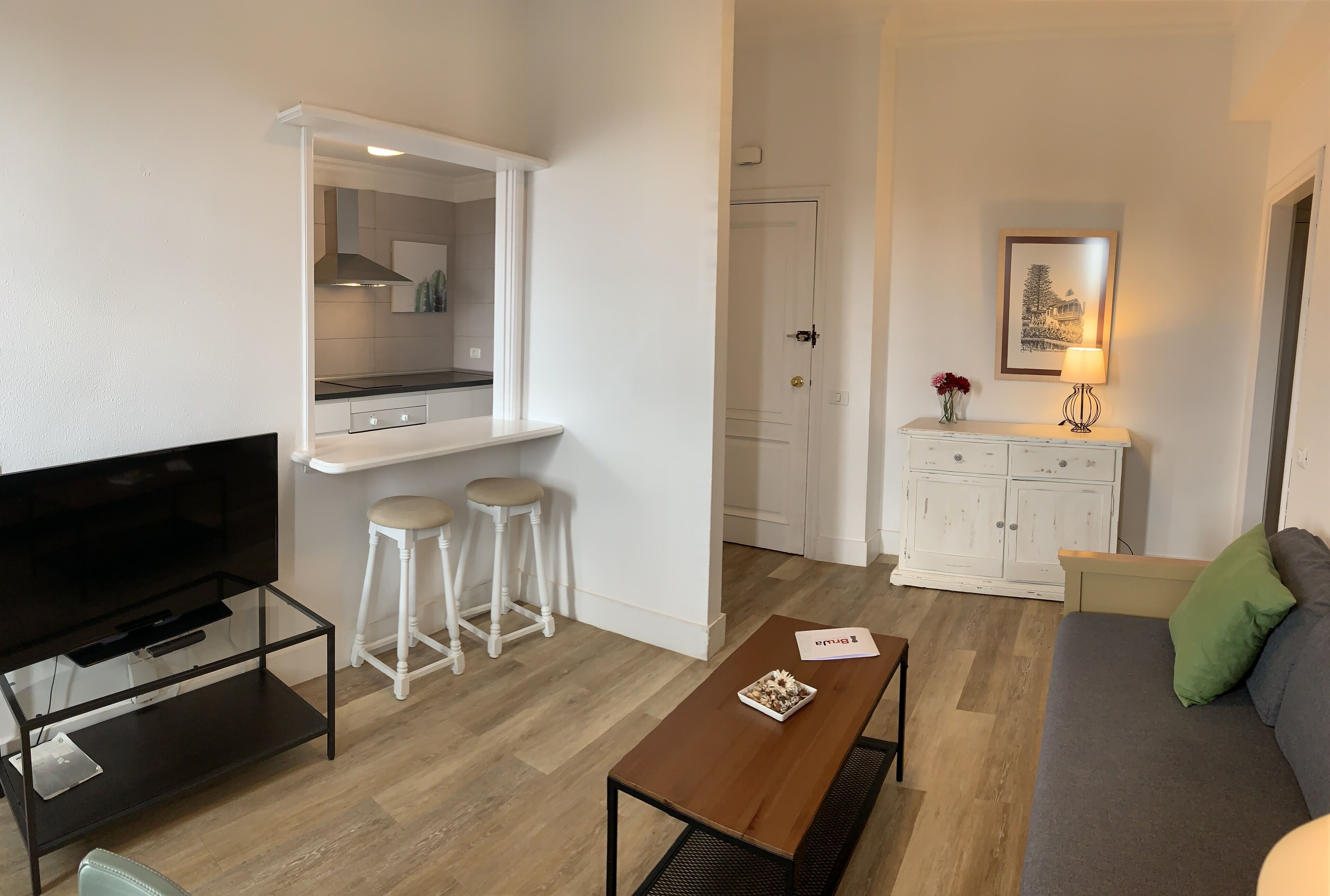 A compact living space with a kitchenette, a sofa, a TV, and a small dining area.