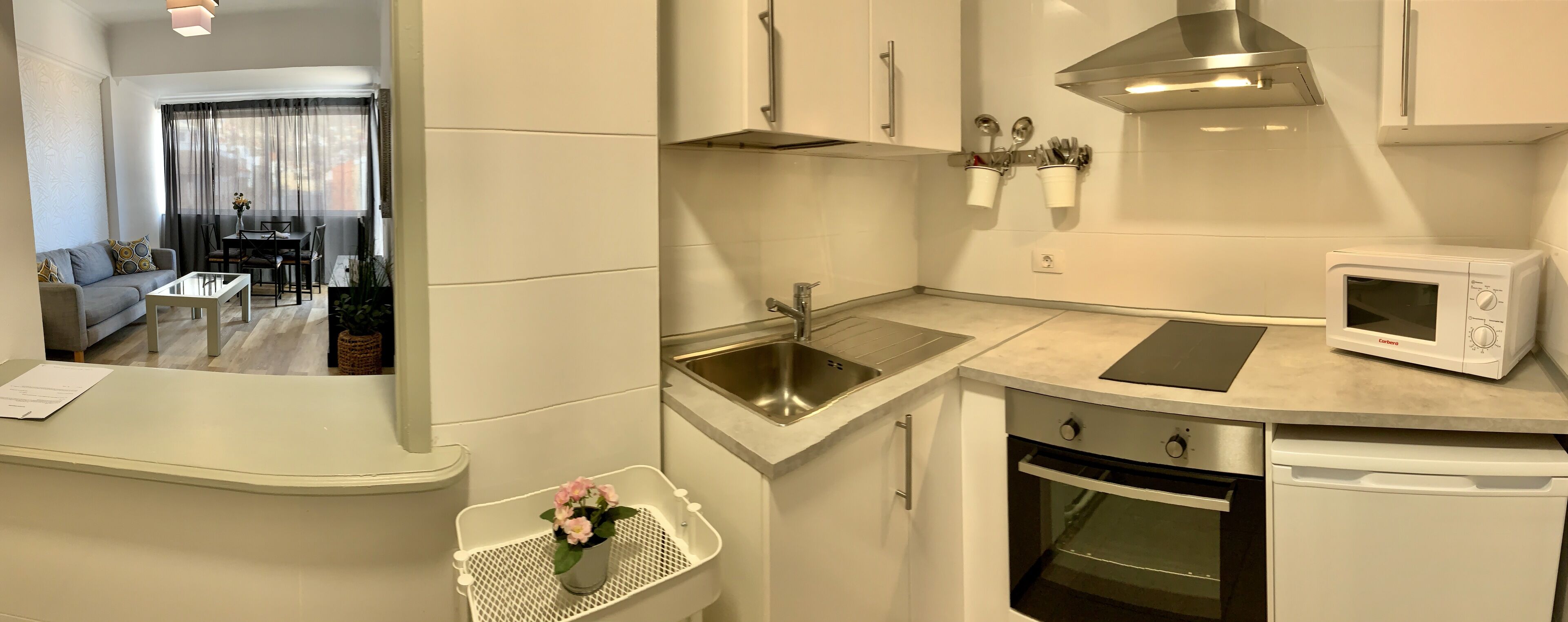 A compact kitchen with a built-in oven, microwave, and stainless steel sink.