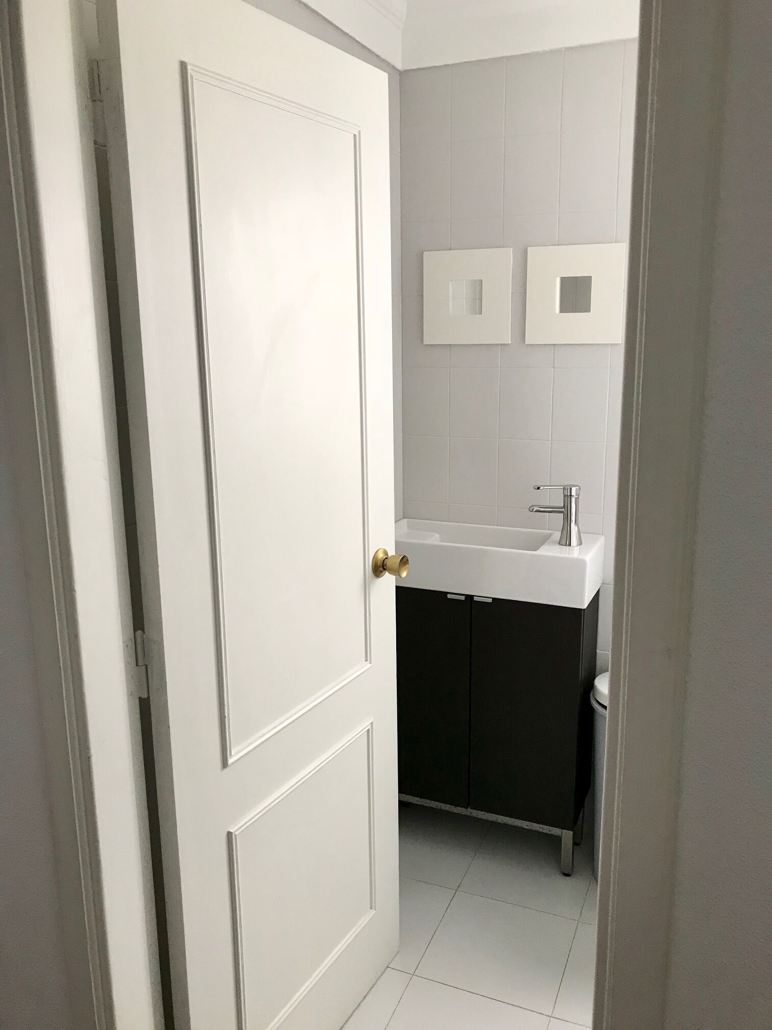 A bathroom with a white door, a sink, and a mirror.
