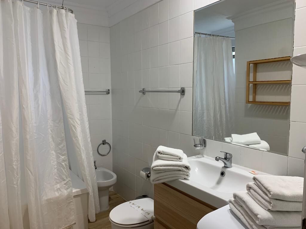 Een badkamer met douchegordijn, wastafel met handdoeken en een spiegel.