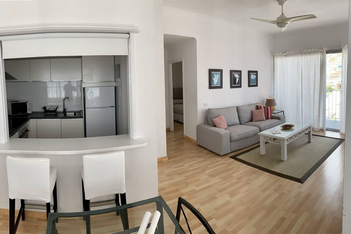 Ein modernes Wohnzimmer mit einer Couch, einem Couchtisch und einem Essbereich mit Stühlen und einem Tisch.
