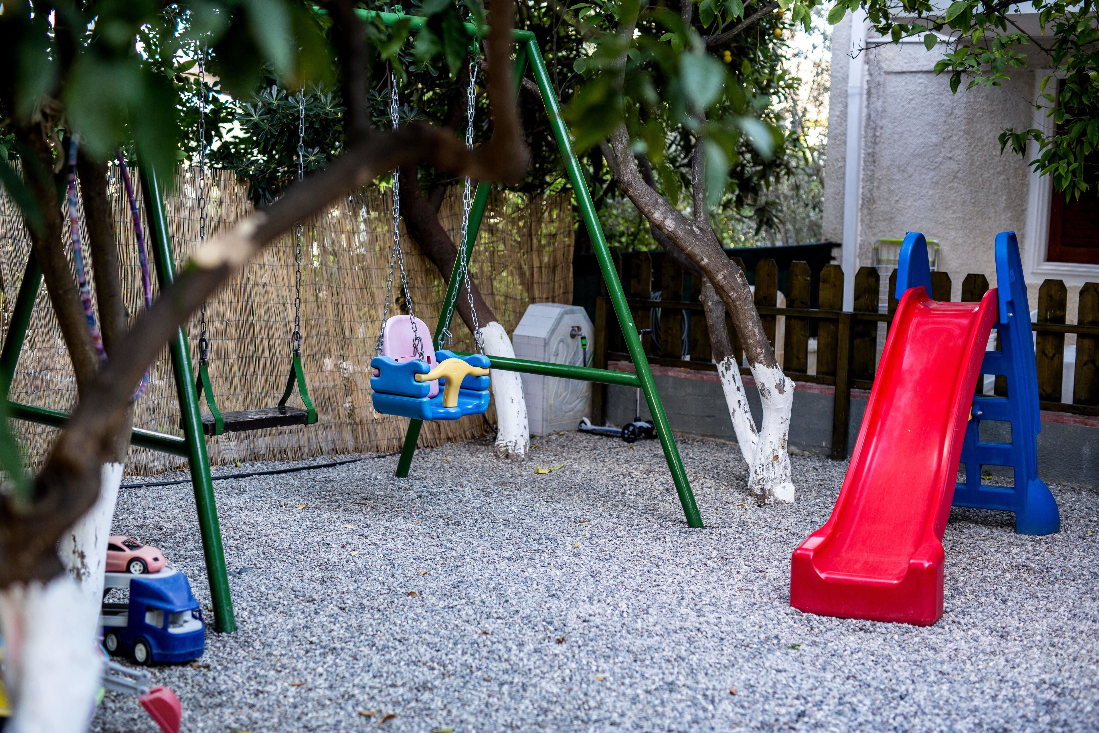 A playground with a swing set, a red slide, and a blue slide.