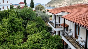 Un hotel con tejido rojo, paredes blancas y balcones con sillas blancas.