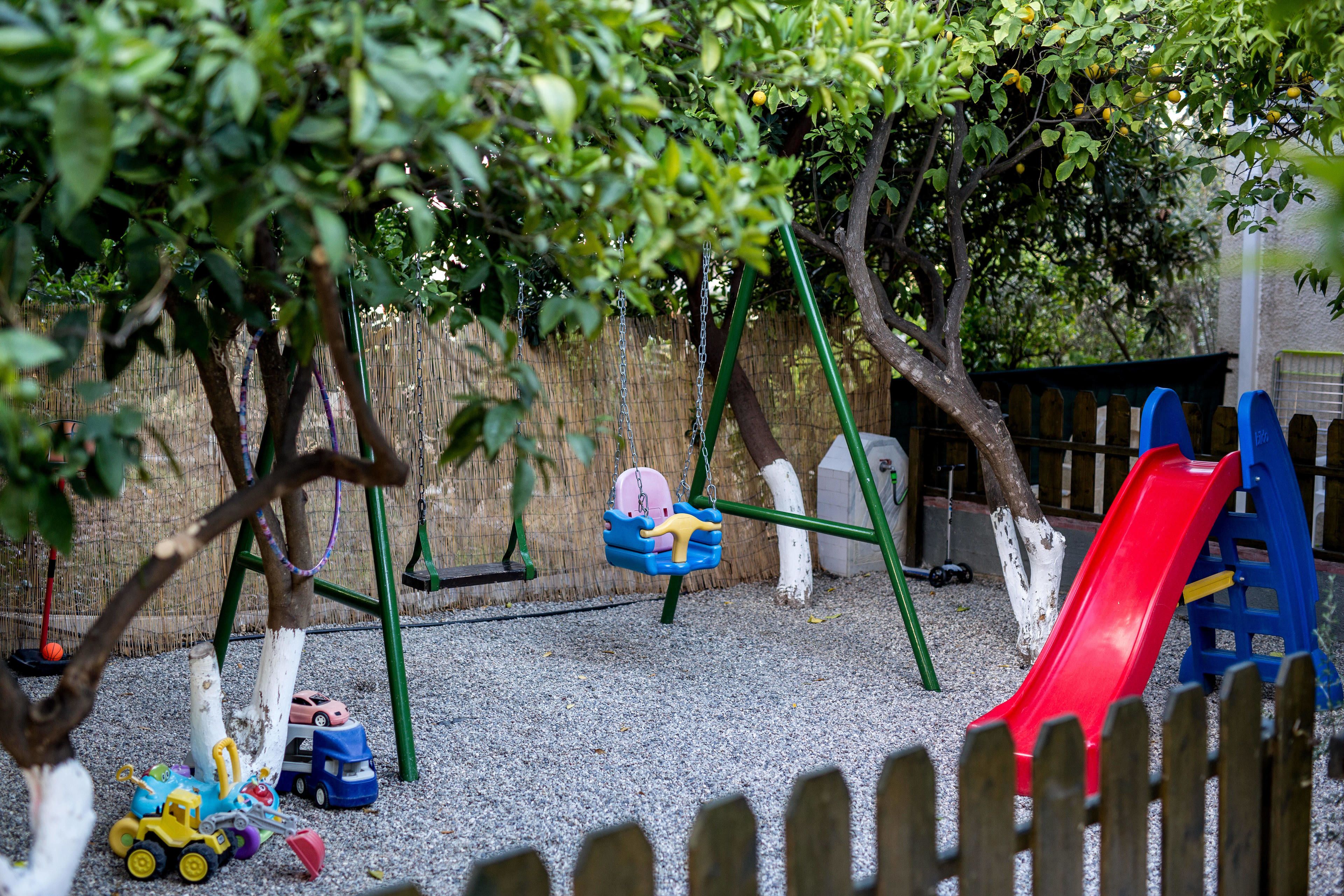 A playground with swings, a slide, and toy vehicles on the ground.