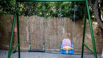 Un columpio con estructura verde y asiento en tonos azul y rosa.