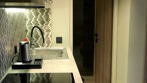 Una cocina moderna con un lavamanos de acero inoxidable, una tetera y una cafetera sobre la encimera.