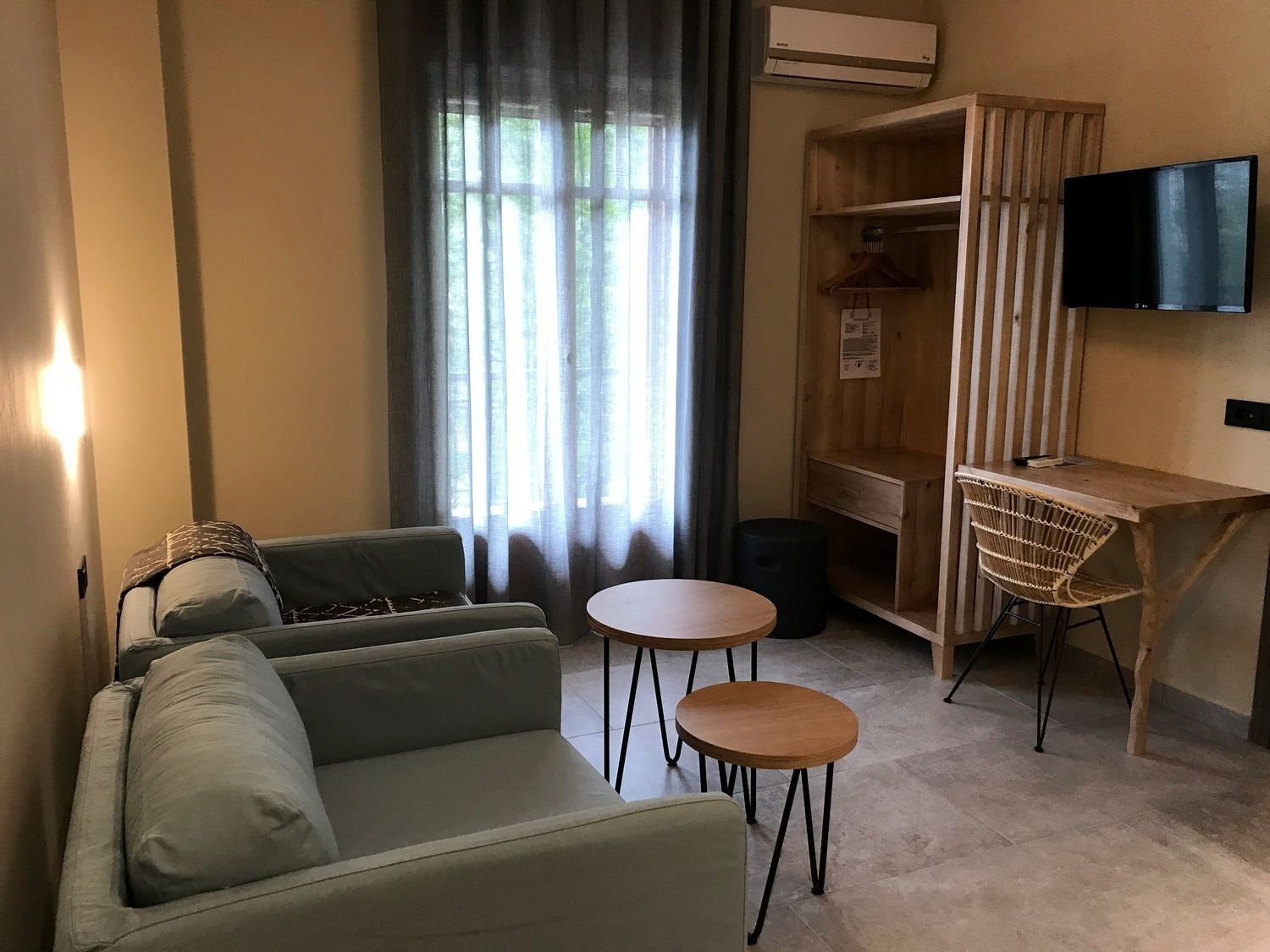 Un salon comprenant un canapé, deux petites tables, un téléviseur et un meuble en bois.