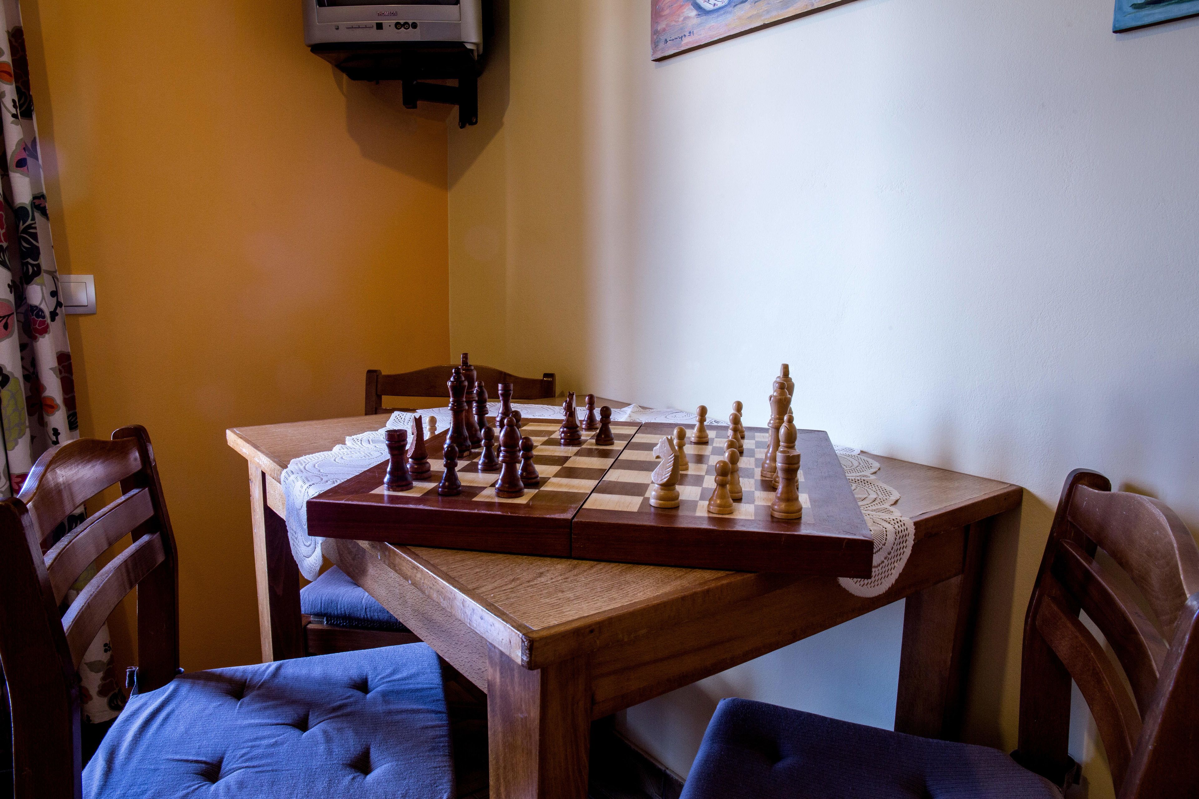 A wooden table with a chessboard, surrounded by upholstered chairs.