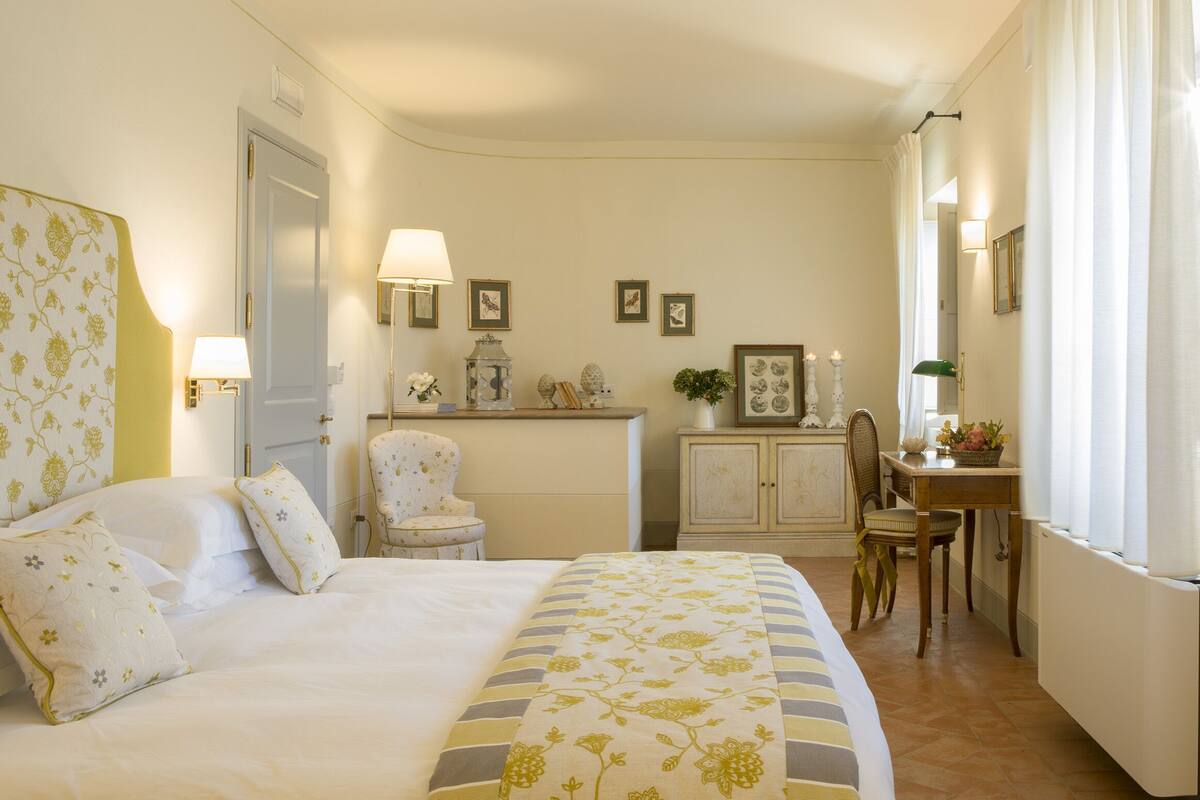 A bedroom with a bed, bedside lamps, a desk, and a chair.