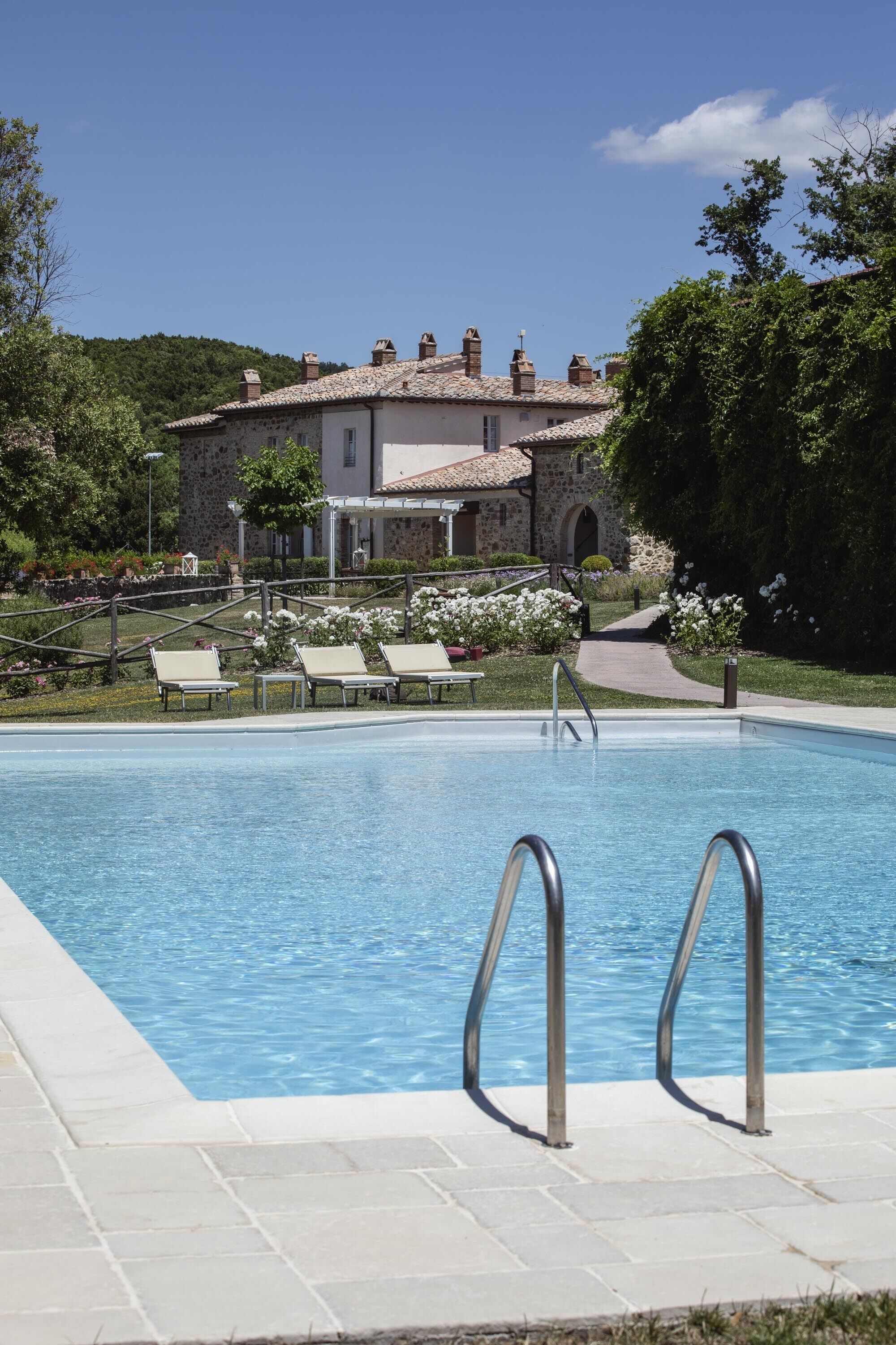 A swimming pool with lounge chairs and a stone building in the background.