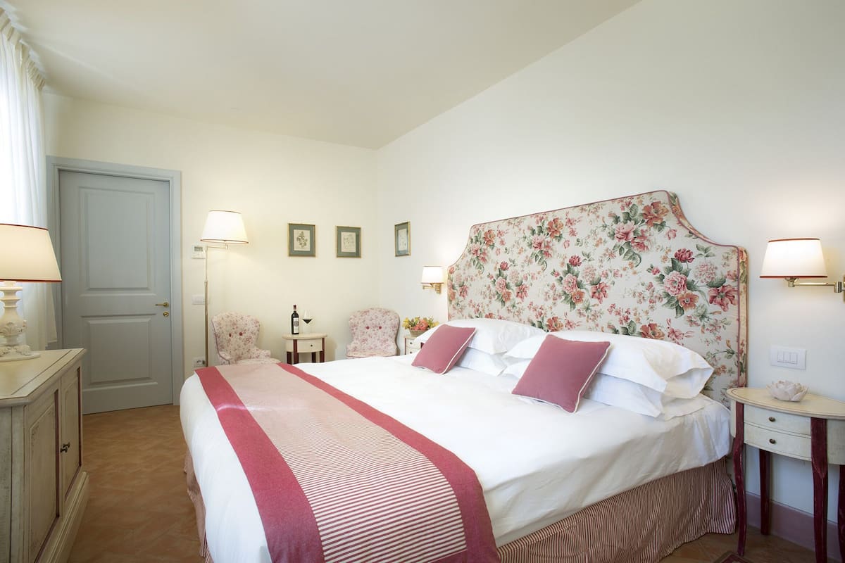 A neatly arranged bedroom with a bed, bedside tables, a chair, and a door.