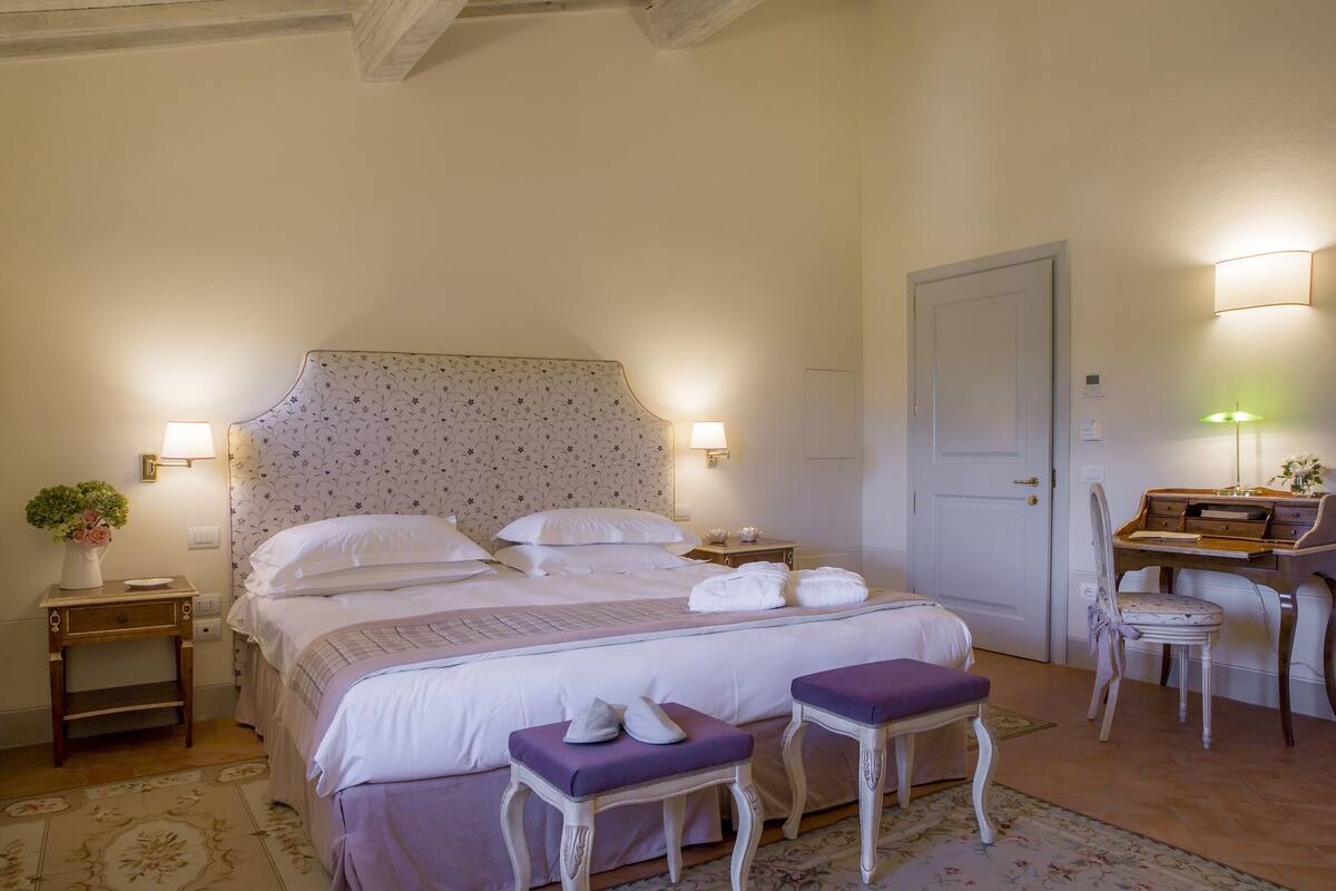 A neatly arranged bedroom with a bed, bedside tables, a desk, and a chair.