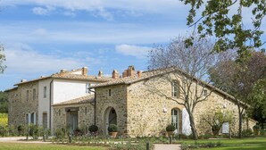 A stone building with a tiled roof, a paved pathway, and a well-maintained garden. - Podere Brizio (Montalcino)