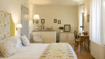 A hotel room with a bed, bedside lamps, a desk, a chair, and a small table with a plant.