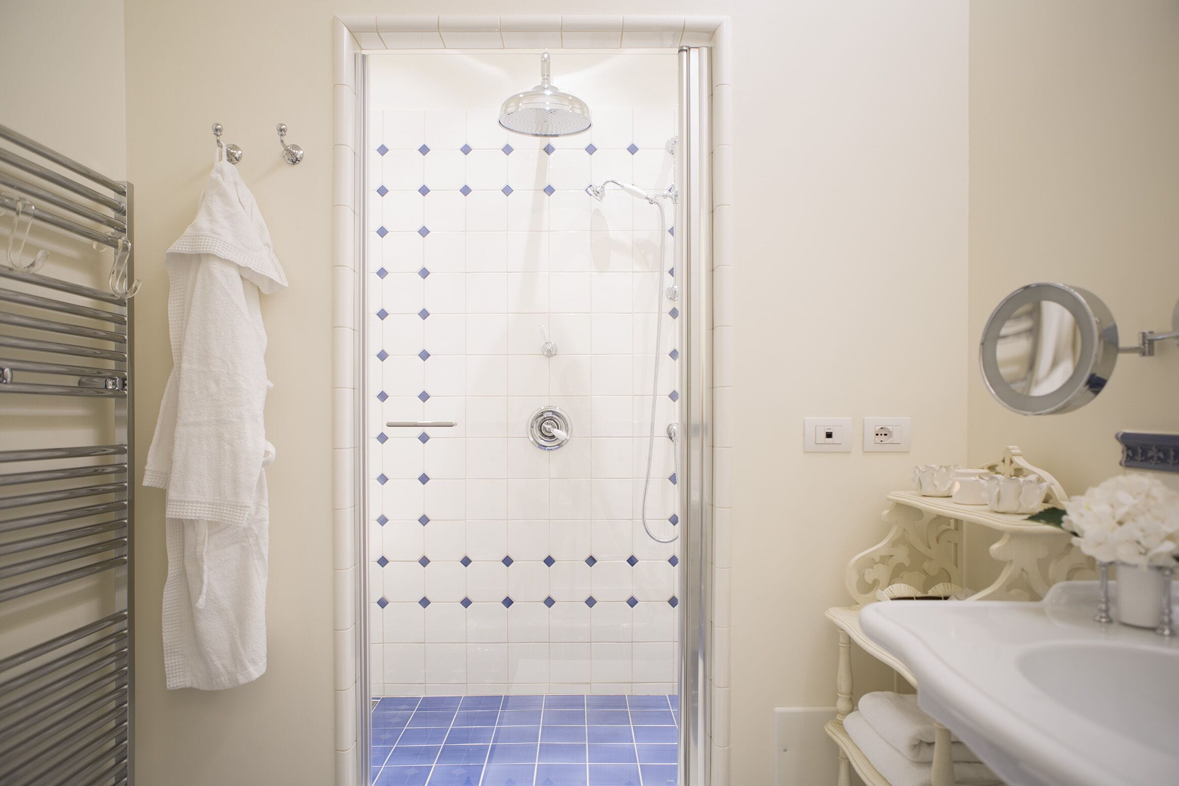A bathroom with a shower, a towel rack, and a sink with a mirror.