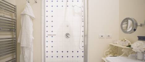 A bathroom with a shower, a towel rack, and a sink with a mirror.