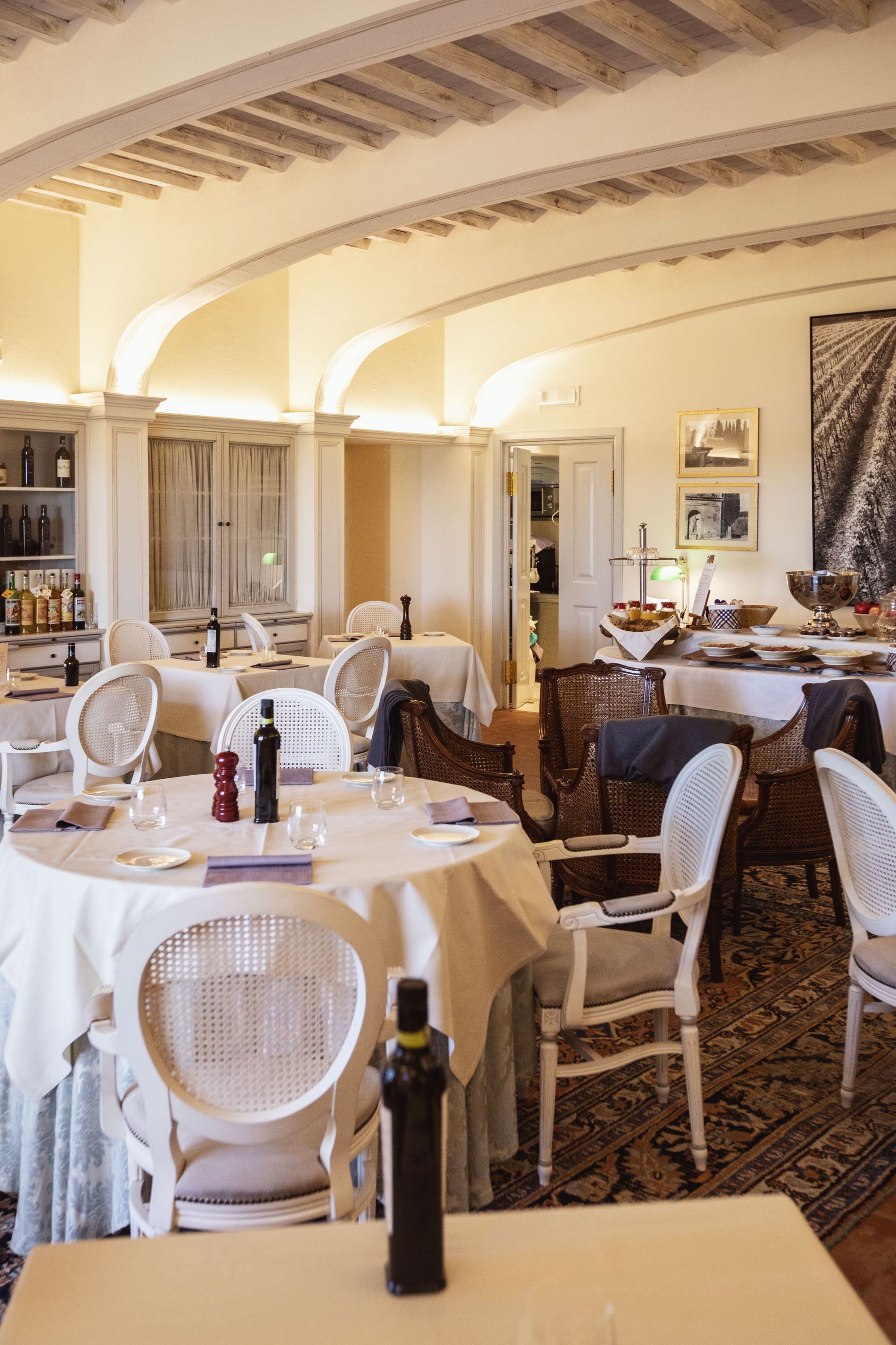 A dining area with round tables, white chairs, and a wooden ceiling.