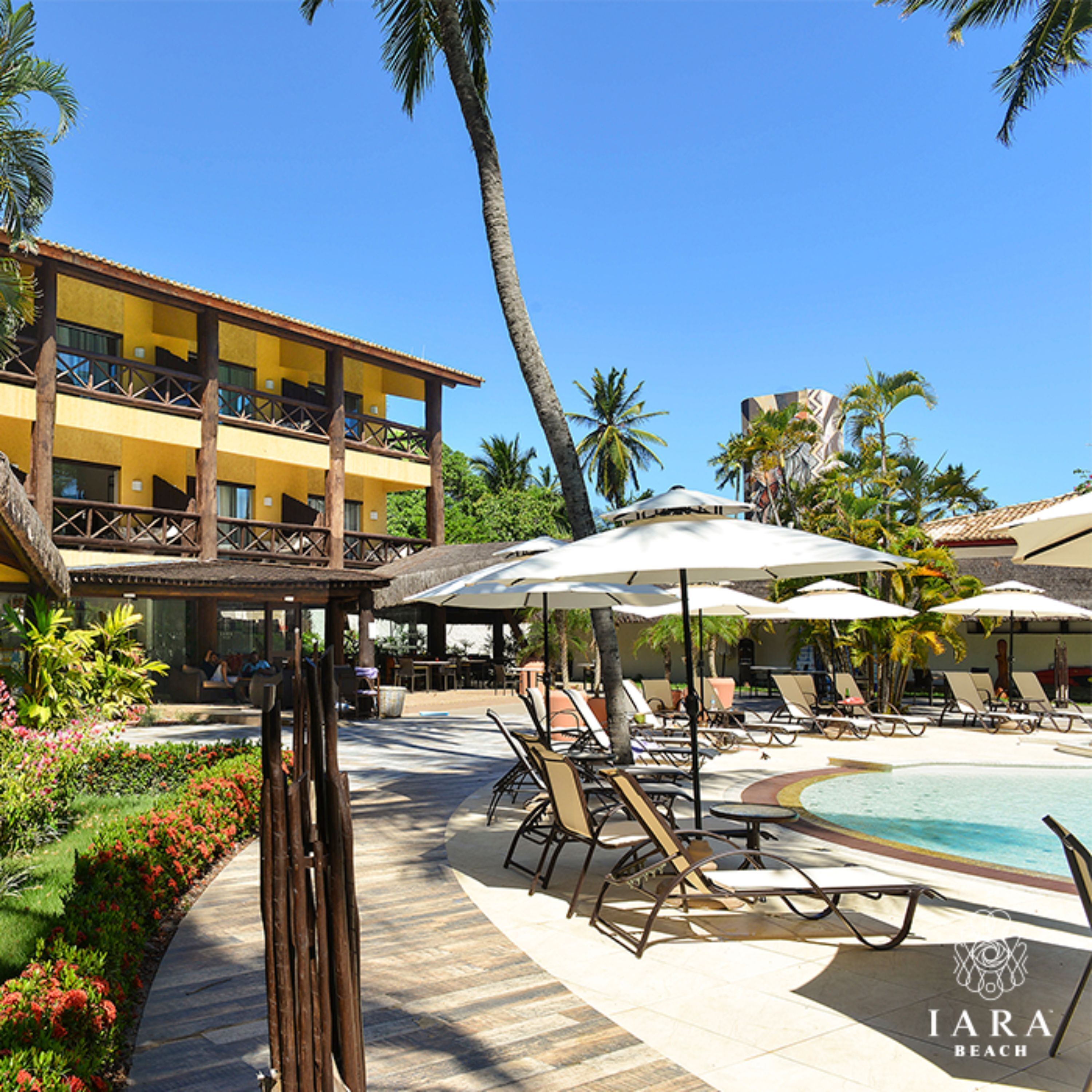 A resort with a pool area, lounge chairs, and a building with balconies.
