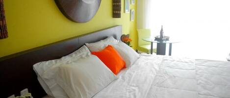 Una habitación de hotel con una cama, un espejo redondo en la pared y una mesita de noche con una lámpara.