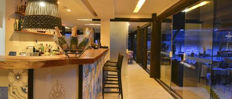A bar area with a counter, chairs, and a large bottle of champagne.