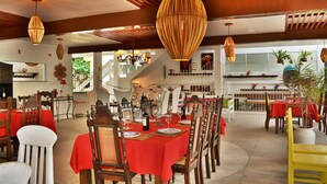 Un restaurante con manteles rojos, sillas de madera y lámparas de mimbre colgantes.