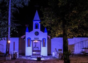 A small church with a bell tower, a cross, and a baptismal font.