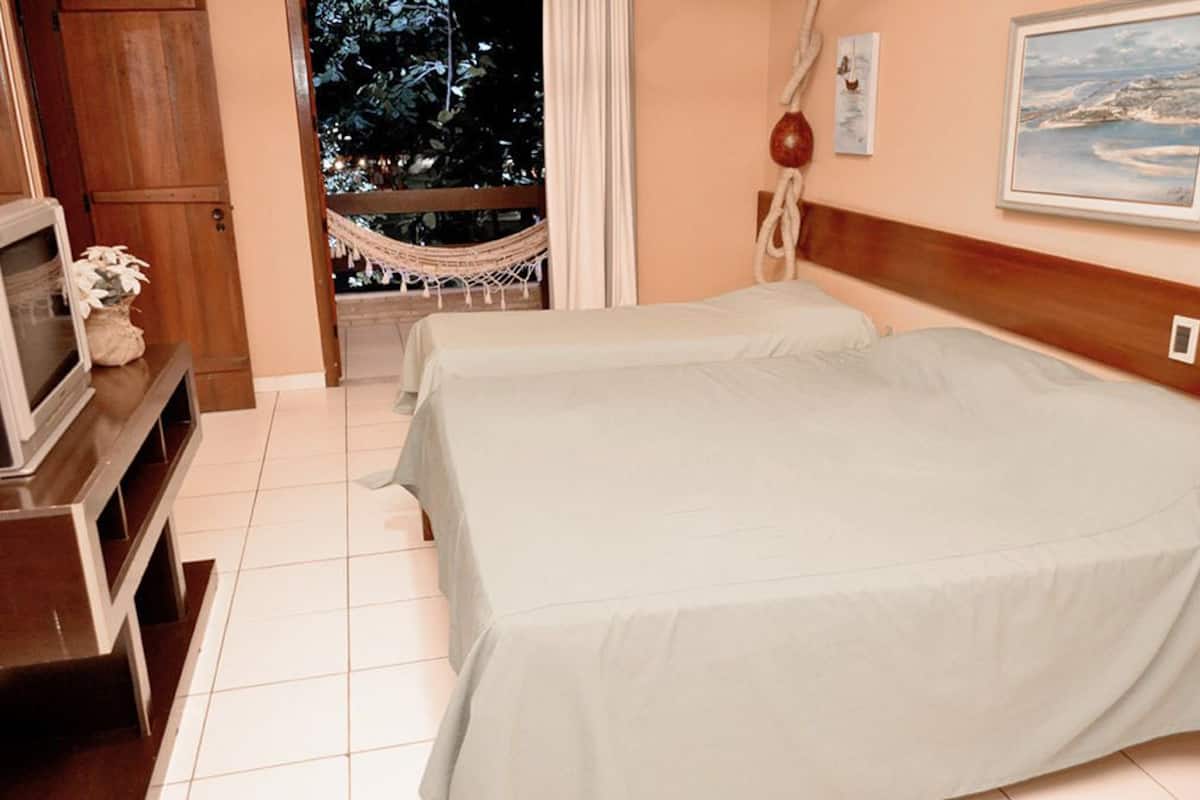 A hotel room with two beds, a TV on a stand, a hammock by the window, and a painting on the wall.