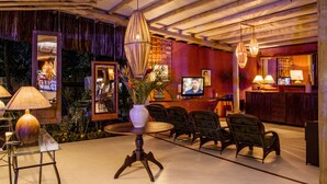 Un espacio lounge moderno con techo de madera, asientos cómodos e iluminación ambiental.