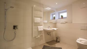 Ein modernes Badezimmer mit Dusche, Toilette, Waschbecken und einem Fenster mit Pflanzen.