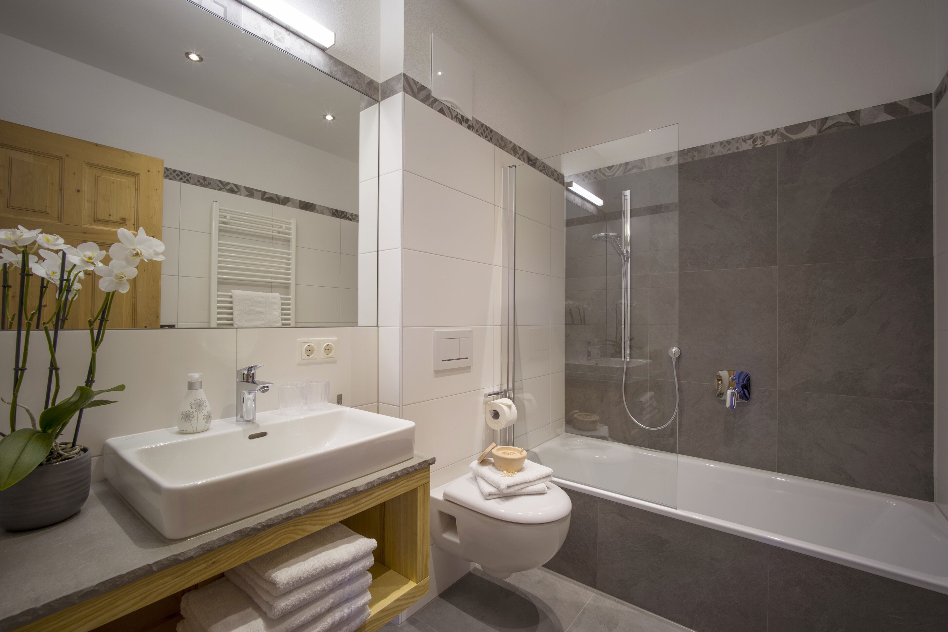 Un baño moderno con un lavamanos blanco, un inodoro y una ducha con mampara de vidrio.
