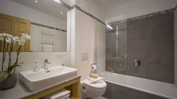 Un baño moderno con un lavamanos blanco, un inodoro y una ducha con mampara de vidrio.