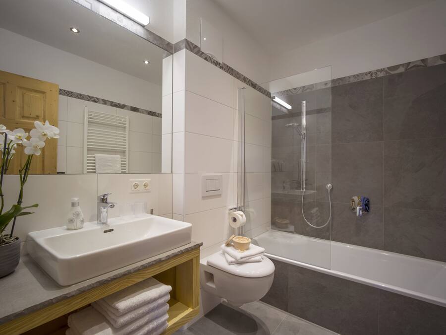 Un baño moderno con un lavamanos blanco, un inodoro y una ducha con mampara de vidrio.