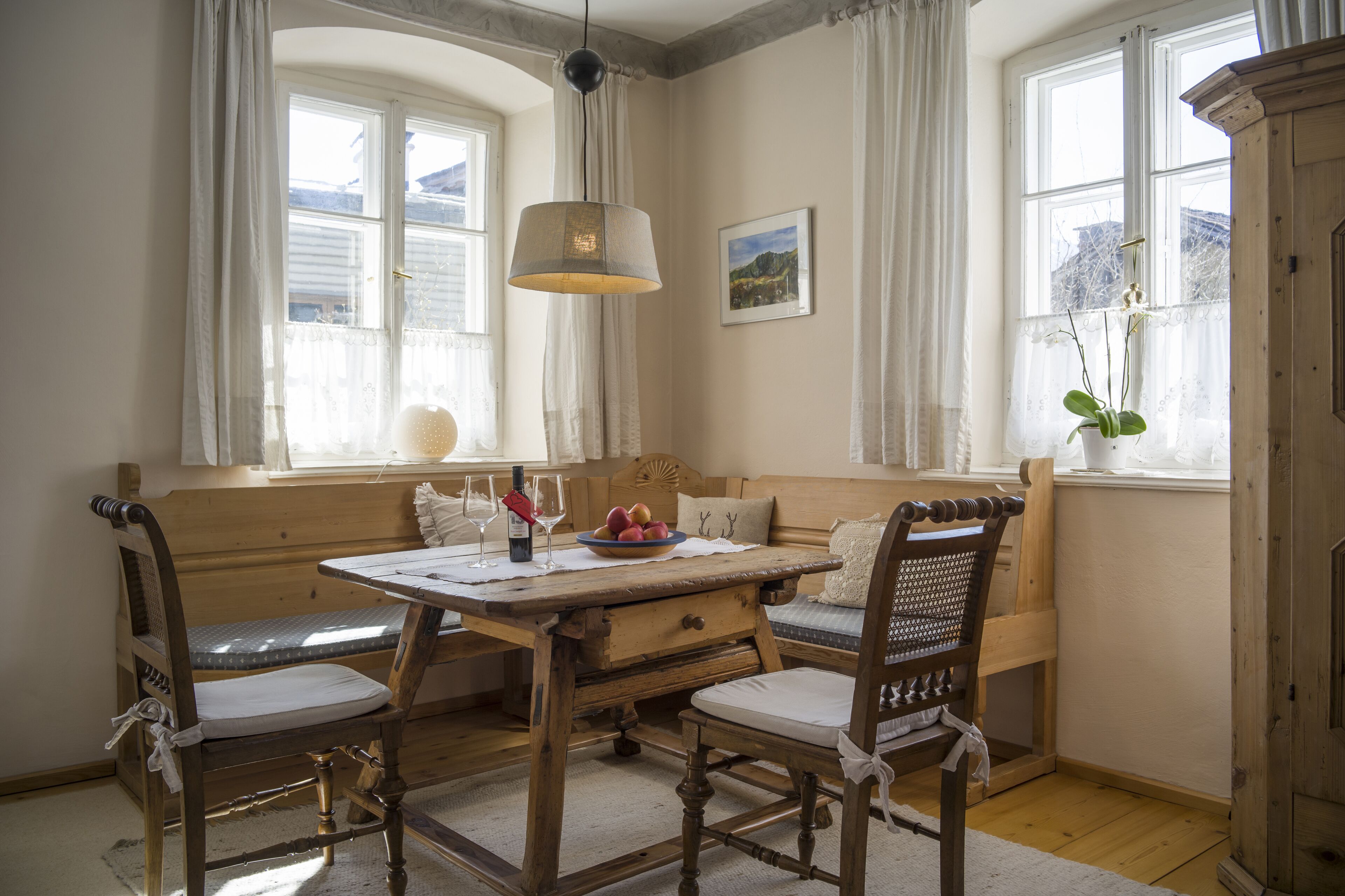 Un coin repas chaleureux avec une table et des chaises en bois, un banc et un luminaire suspendu.
