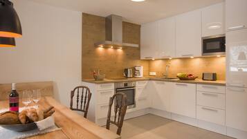 A modern kitchen with white cabinets, a wooden countertop, a built-in oven, and a microwave.