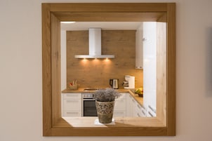 Una cocina con armarios de madera, una estufa y una campana extractora blanca.