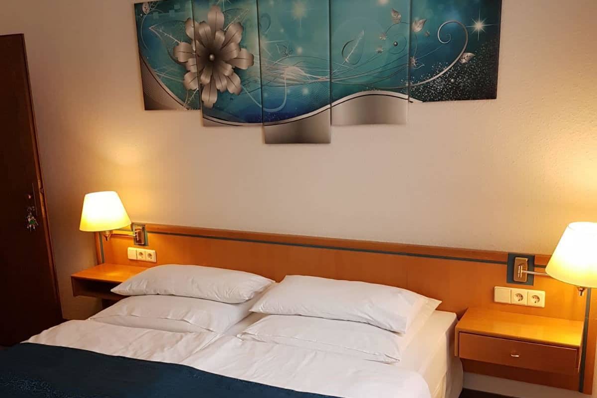 A hotel room with a large bed, two bedside tables with lamps, and a wall-mounted artwork.
