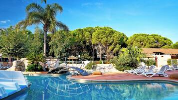 Relax by the serene pool surrounded by lush greenery and palm trees.