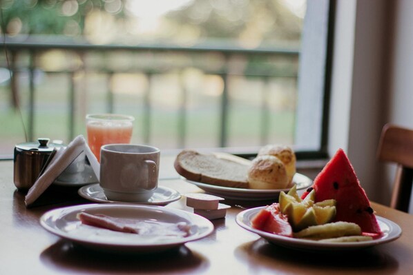 A breakfast table with plates of food, a cup, and a glass of juice.