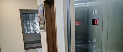 Un ascensor con pantalla digital y barandilla metálica.
