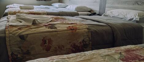 A hotel room with two beds, a window with curtains, and a wooden headboard.