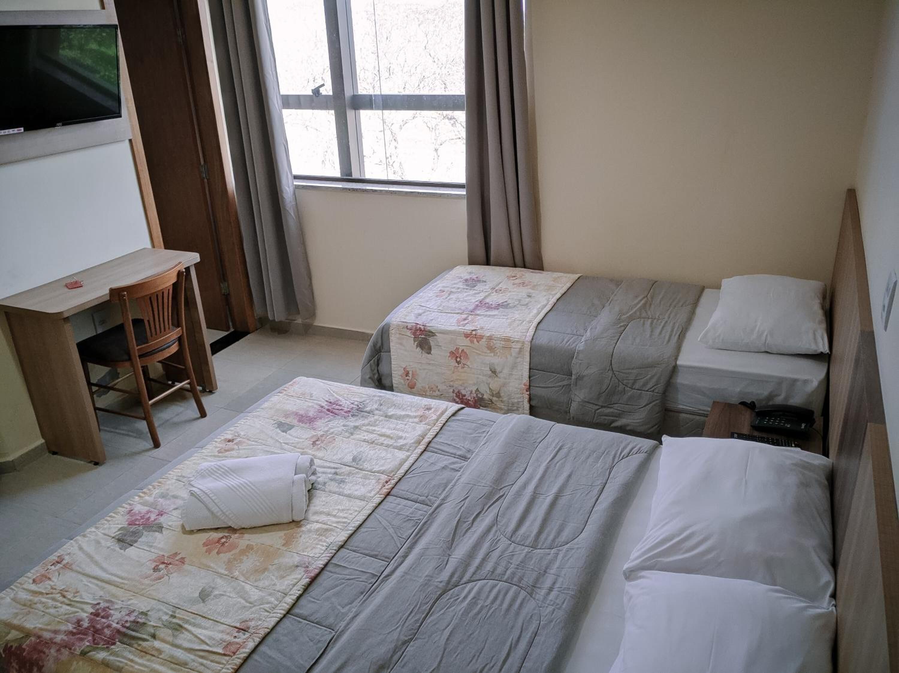 A hotel room with two beds, a desk, and a chair.
