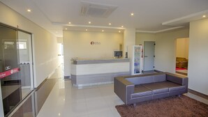 A modern hotel lobby with a reception desk, a sofa, and a vending machine. - Rede Andrade Biton (Foz do Iguaçu)