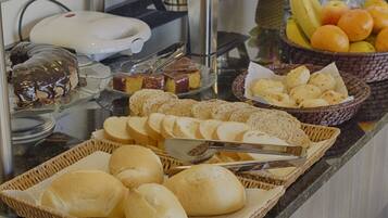 Un bufé con panes, pasteles y frutas variadas.