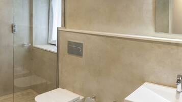 Un baño moderno con cabina de ducha de vidrio, dos bidés y un espejo grande sobre un lavabo.
