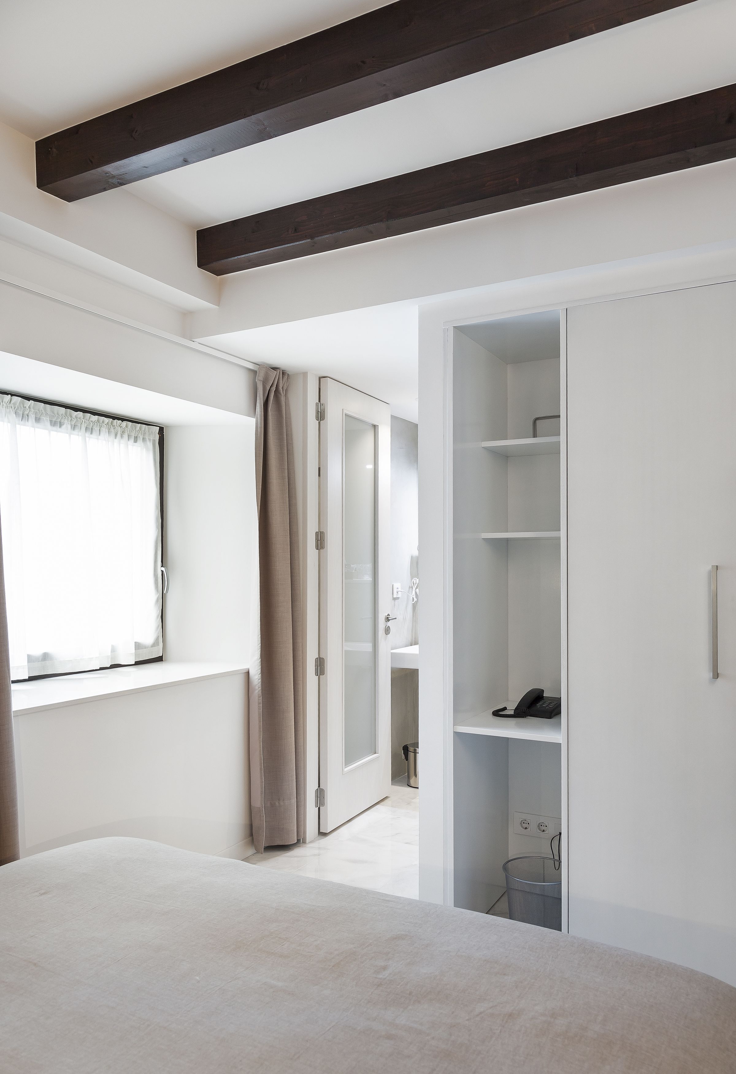 A bedroom with a large bed, a wardrobe, and a window with curtains.