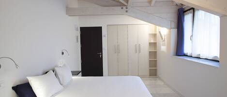 Un dormitorio con cama, armario y ventana con cortinas.