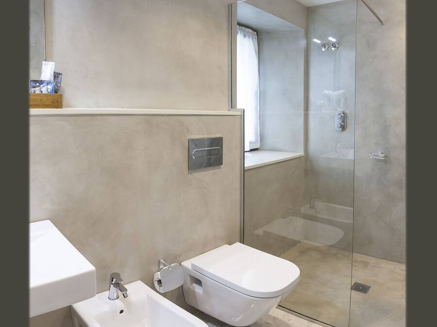 Un baño moderno con inodoro, lavabo y ducha con mampara de vidrio.