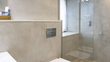 Un baño moderno con cabina de ducha de vidrio, inodoro blanco y lavamanos.