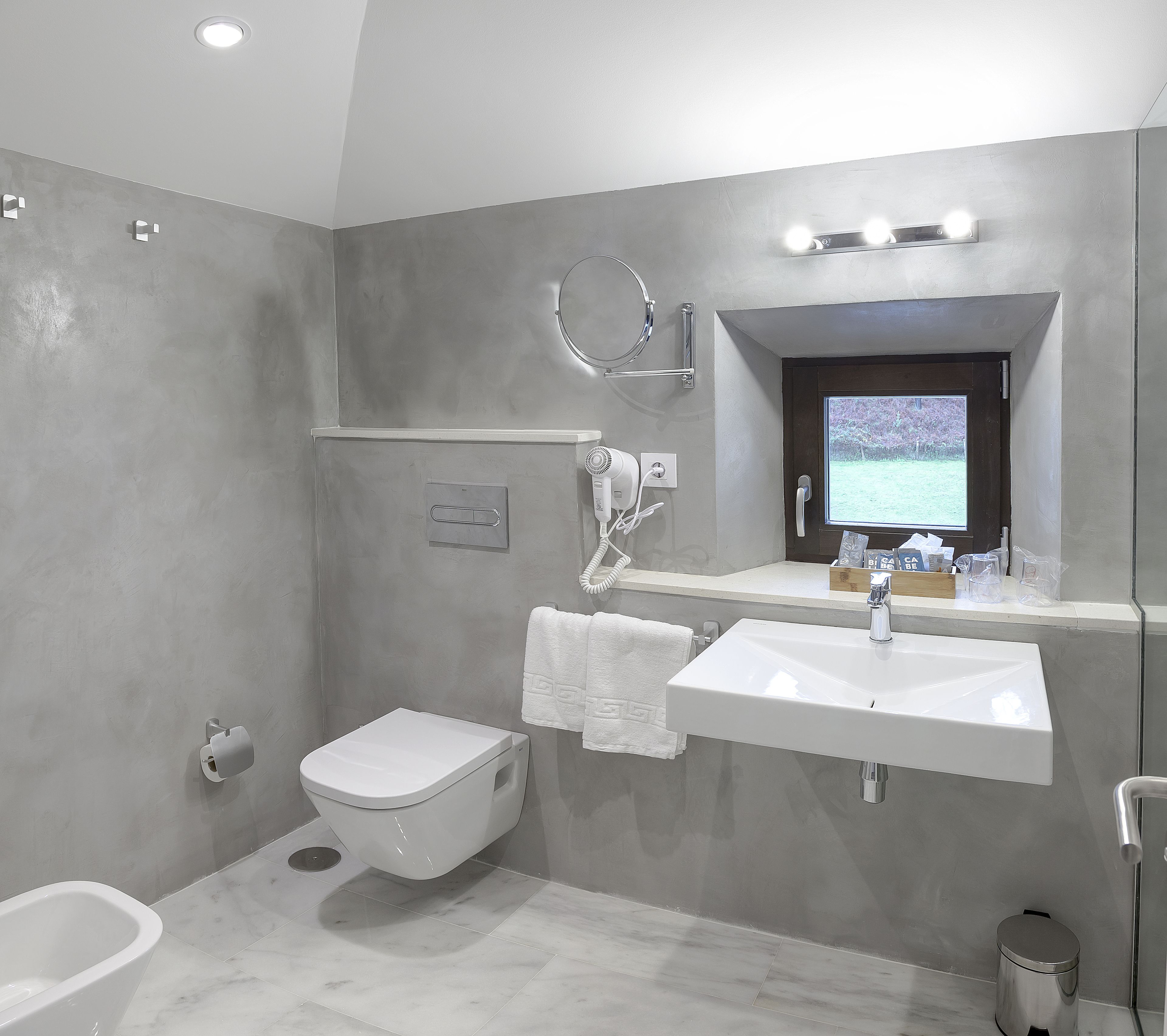 Un baño moderno con inodoro, bidé, lavamanos y ducha.