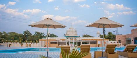 Una piscina al aire libre, sombrillas, sillones reclinables de piscina